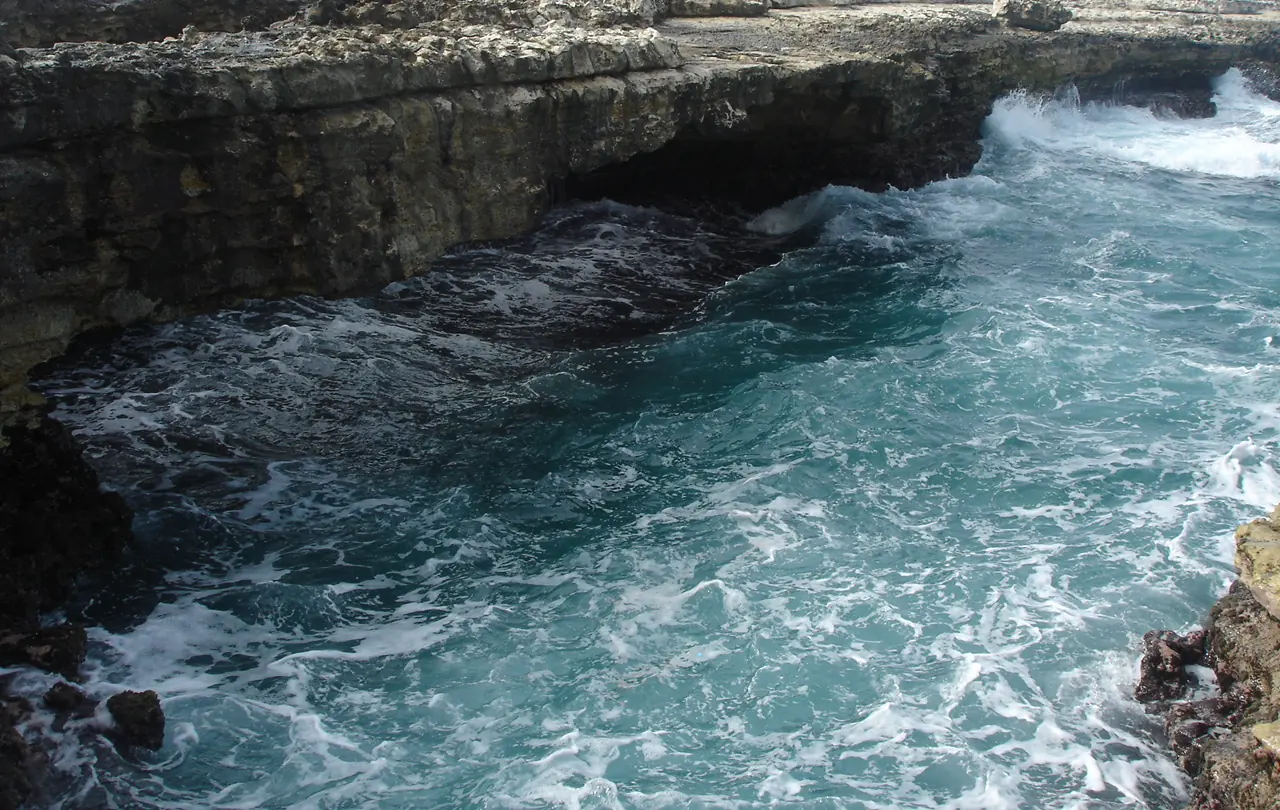 Atlantic waves breaking under the limestone arch of Devil's Bridge on the east coast of Antigua